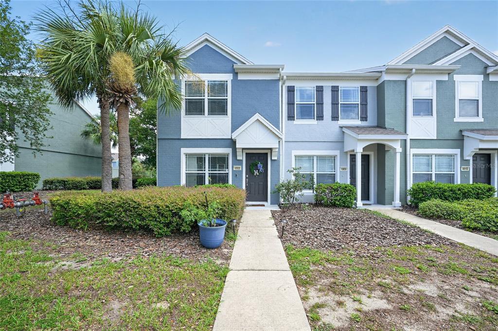 A two-story townhouse exterior features blue siding, a palm tree, and a concrete walkway — 4908 SW 45TH CIRCLE, OCALA, FL