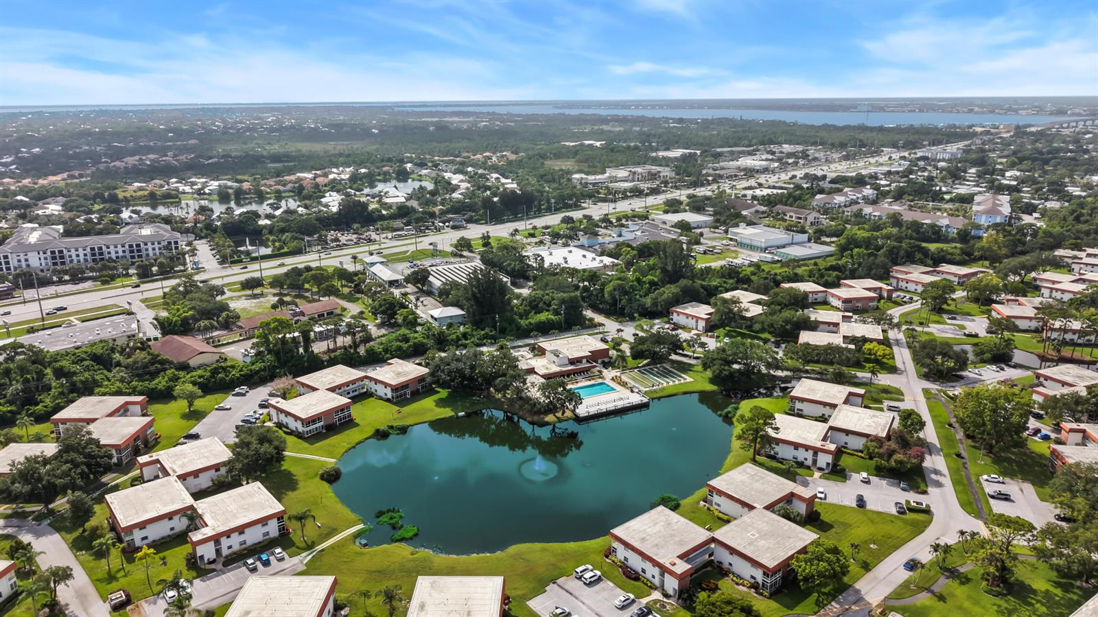An aerial view shows a residential complex with multiple buildings surrounding a central pond — 1225 NW 21st Street # 1708, Stuart FL 34994, STUART, FL