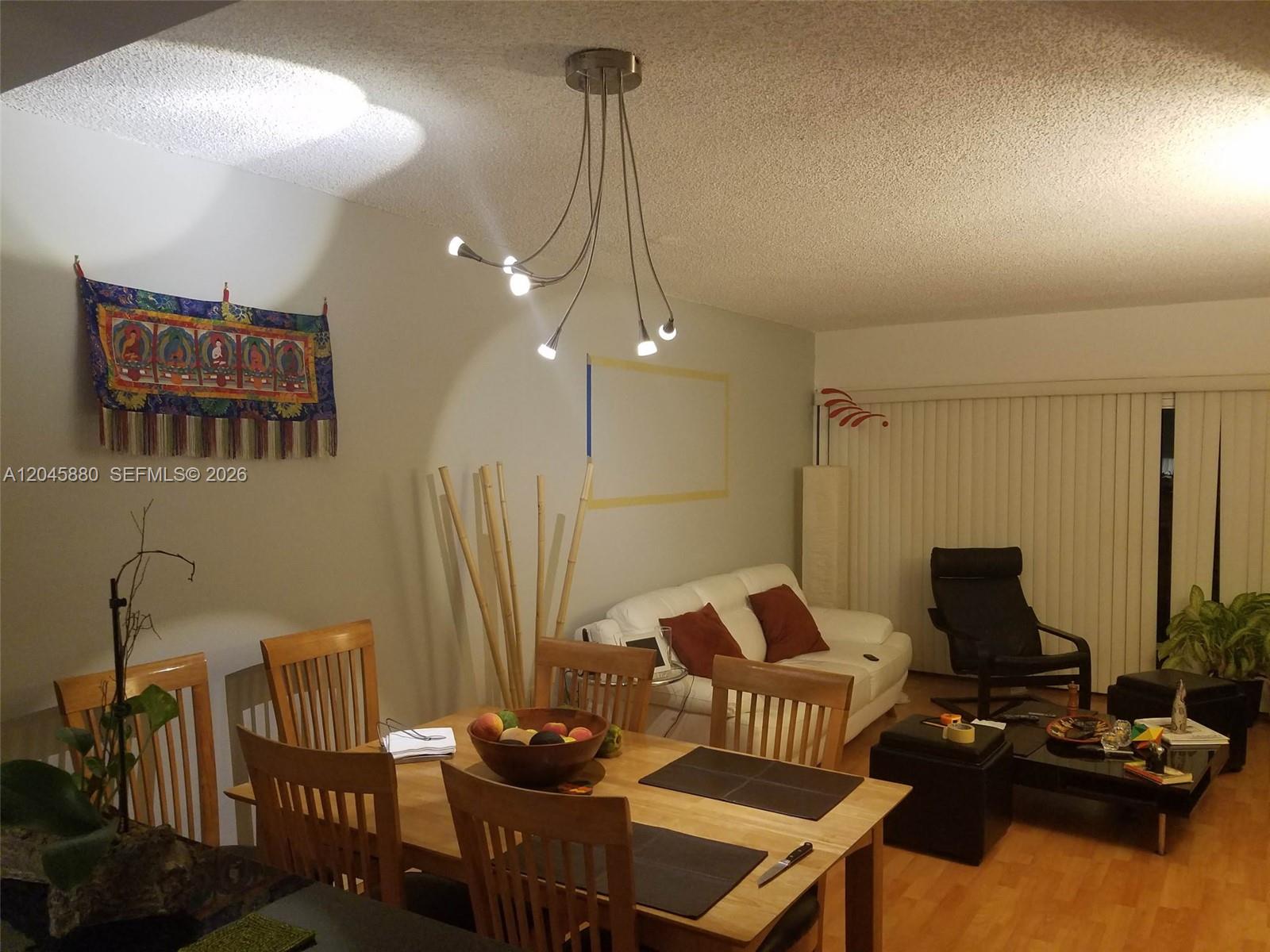 A dining area with a wooden table and chairs sits adjacent to a living space — 9371 Fontainebleau Blvd # I208, Miami FL 33172, MIAMI, FL