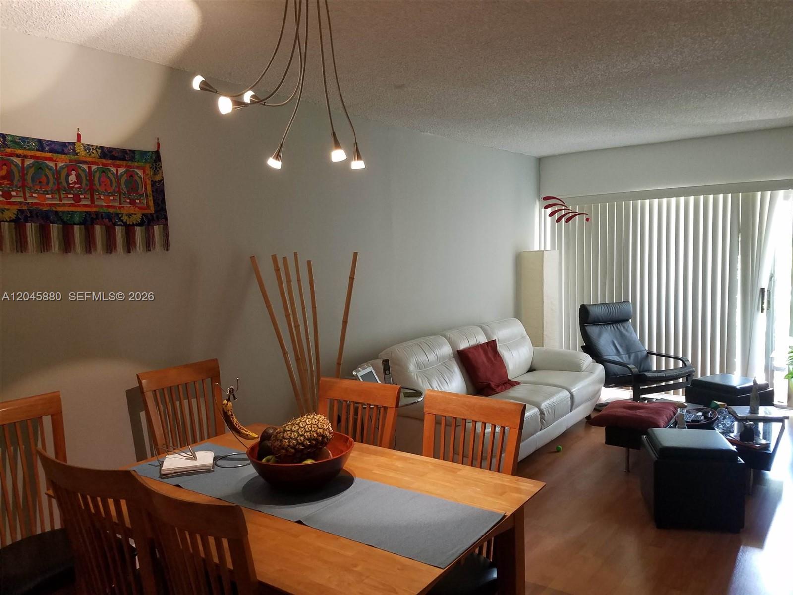 A dining area with a wooden table and chairs sits adjacent to a living room — 9371 Fontainebleau Blvd # I208, Miami FL 33172, MIAMI, FL