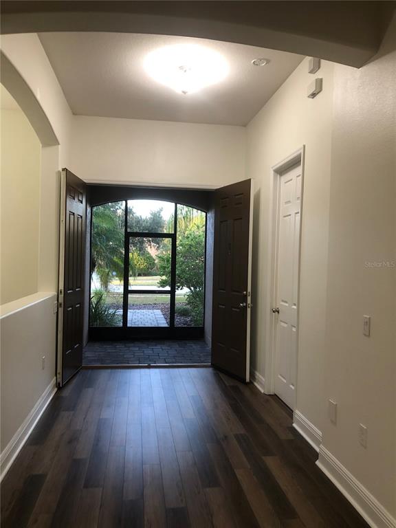An entryway with dark wood-look flooring leads to a screened-in porch through double doors — 2360 EAGLE TALON COURT, KISSIMMEE, FL