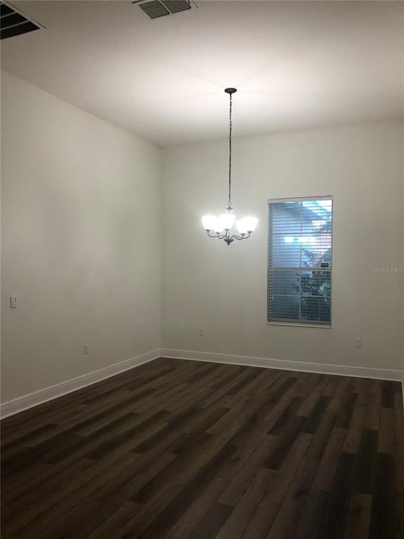A dining room with white walls, dark wood-look flooring, and a hanging chandelier — 2360 EAGLE TALON COURT, KISSIMMEE, FL