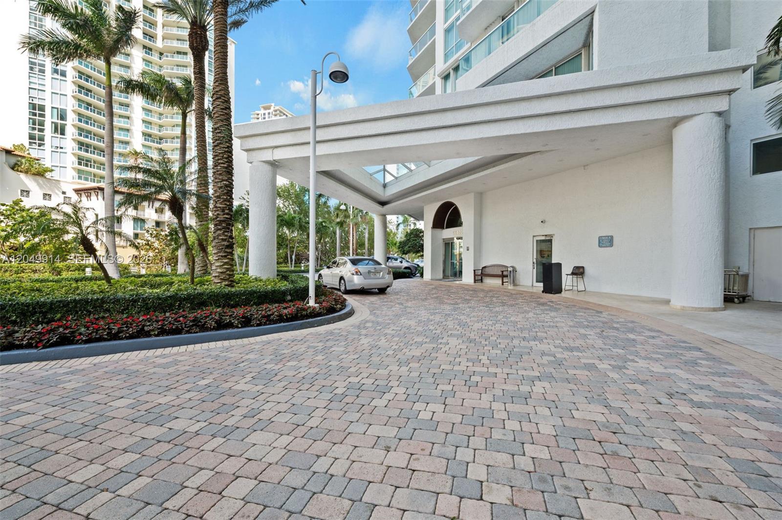 A paved driveway leads to the covered entrance of a multi-story white residential building — 16400 Collins Ave # 1644, Sunny Isles Beach FL 33160, SUNNY ISLES BEACH, FL