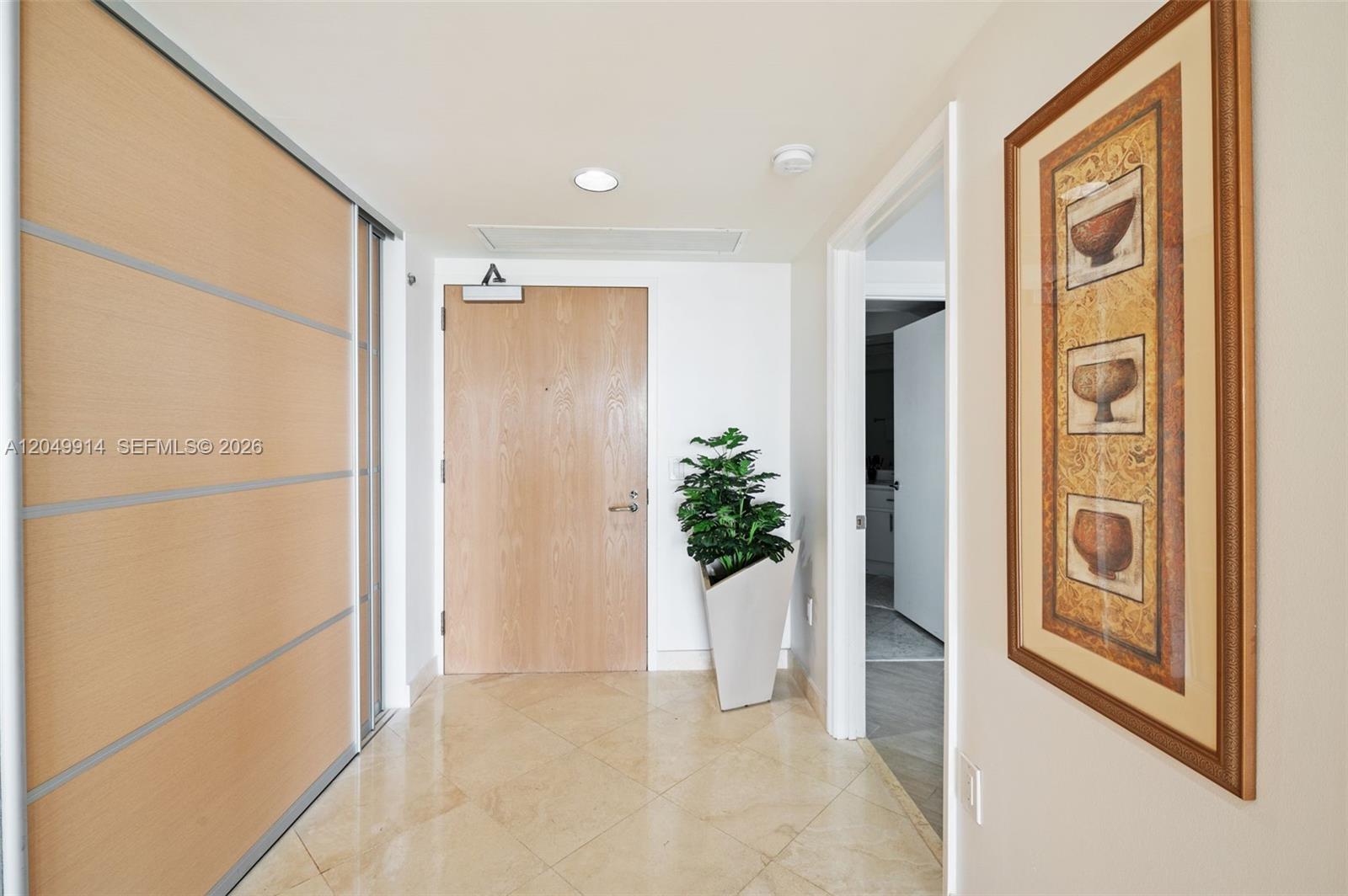 A tiled entryway features a wooden door, a large potted plant, and framed wall art — 16400 Collins Ave # 1644, Sunny Isles Beach FL 33160, SUNNY ISLES BEACH, FL