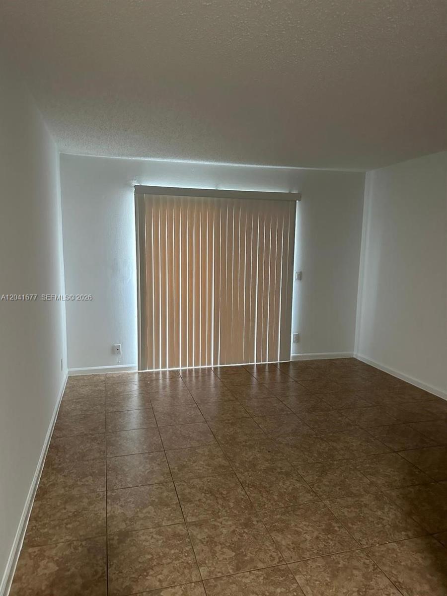 An empty room features light-colored walls, a tiled floor, and vertical blinds over a sliding door — 1500 N Congress Ave # B44, West Palm Beach FL 33401, WEST PALM BEACH, FL