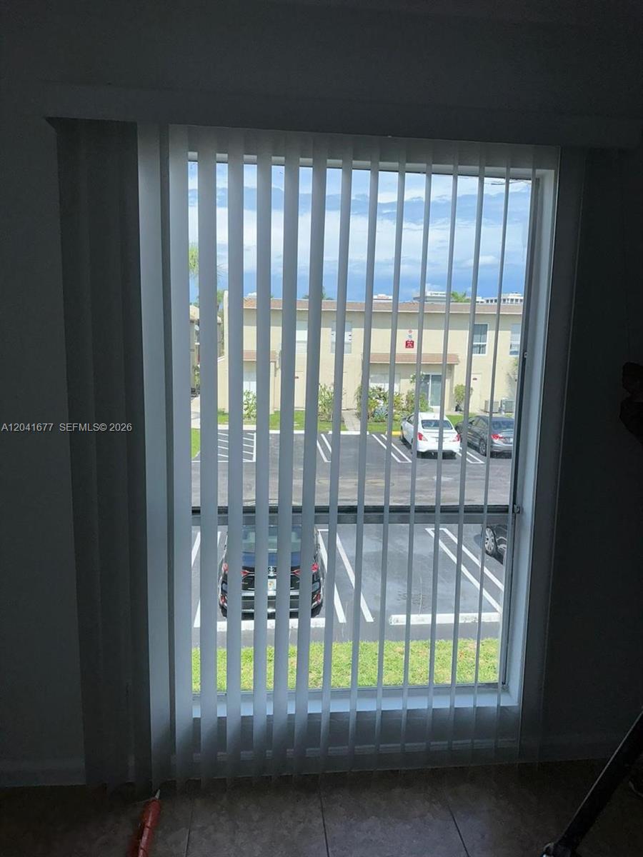 A window with vertical blinds overlooks a parking lot and a multi-story apartment building — 1500 N Congress Ave # B44, West Palm Beach FL 33401, WEST PALM BEACH, FL