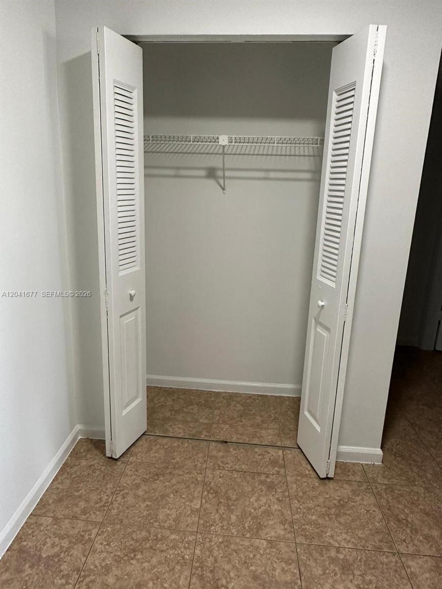 An open closet with white louvered doors and a wire shelf sits on tiled flooring — 1500 N Congress Ave # B44, West Palm Beach FL 33401, WEST PALM BEACH, FL