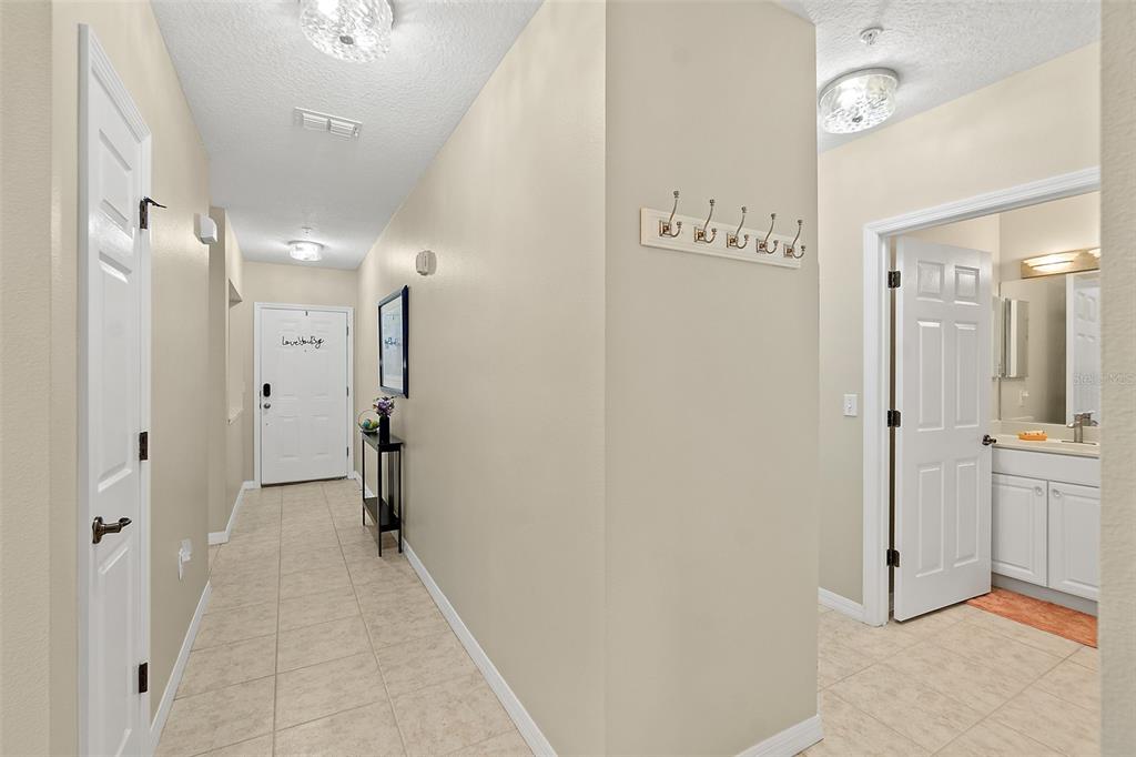 A tiled entryway features a white front door, a narrow console table, and a bathroom entrance — 1000 CANOPY WALK LANE UNIT 1013, PALM COAST, FL