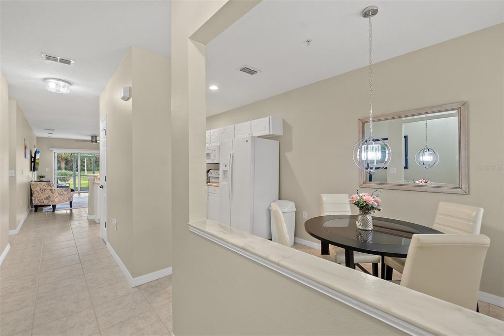 A dining area with a round table and mirror, adjacent to a hallway and kitchen — 1000 CANOPY WALK LANE UNIT 1013, PALM COAST, FL