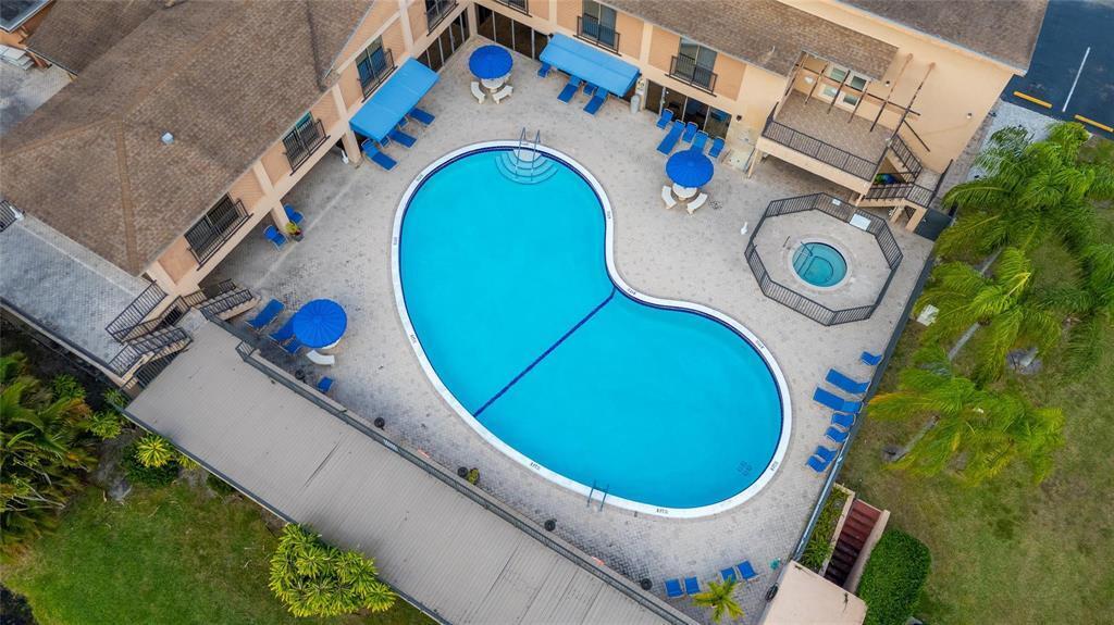 An aerial view shows a kidney-shaped swimming pool and a hot tub on a patio — 480 NW 76th Avenue # 205, Margate FL 33063, MARGATE, FL