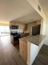 A kitchen features light wood cabinets, granite countertops, and a breakfast bar overlooking the living area — 1680 NW 4th Ave # 8B, Miami FL 33136, MIAMI, FL