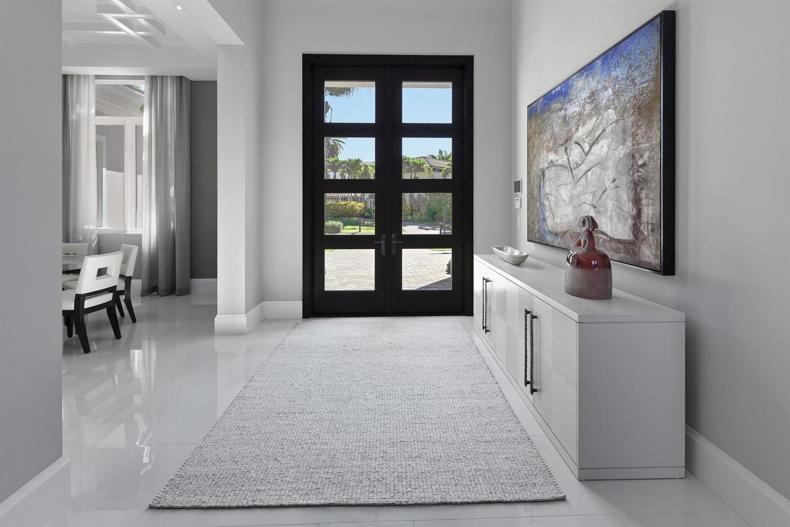 A bright entryway features a white console table, a large abstract painting, and double doors — 17661 Scarsdale Way, Boca Raton FL 33496, BOCA RATON, FL