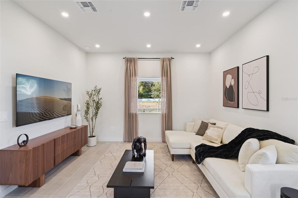 A modern living room features a white sectional sofa, a dark wood media console, and a television — 455 SKYFIELD COURT, LADY LAKE, FL
