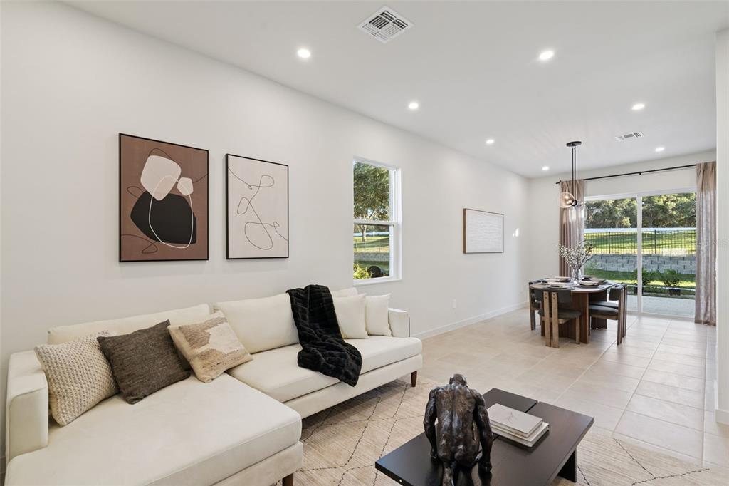 A living room with a white sectional sofa, coffee table, and dining area with sliding doors — 455 SKYFIELD COURT, LADY LAKE, FL
