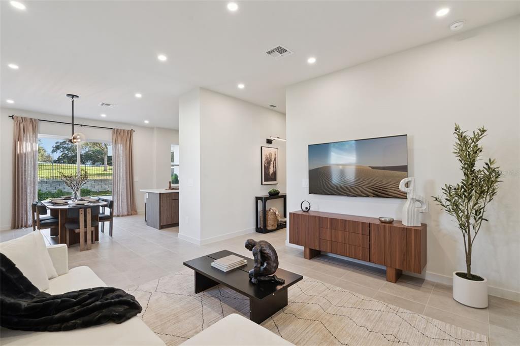 A modern living room features a wall-mounted television, wooden media console, and adjacent dining area — 455 SKYFIELD COURT, LADY LAKE, FL