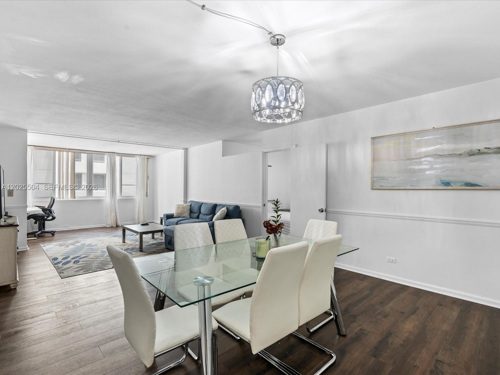 A dining area with a glass table and chairs opens into a living room space — 5005 Collins Ave # 222, Miami Beach FL 33140, MIAMI BEACH, FL