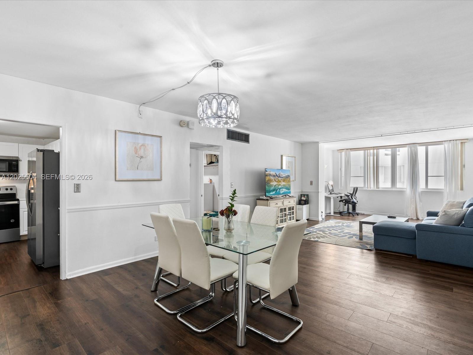 A dining area with a glass table and white chairs opens into a living room — 5005 Collins Ave # 222, Miami Beach FL 33140, MIAMI BEACH, FL
