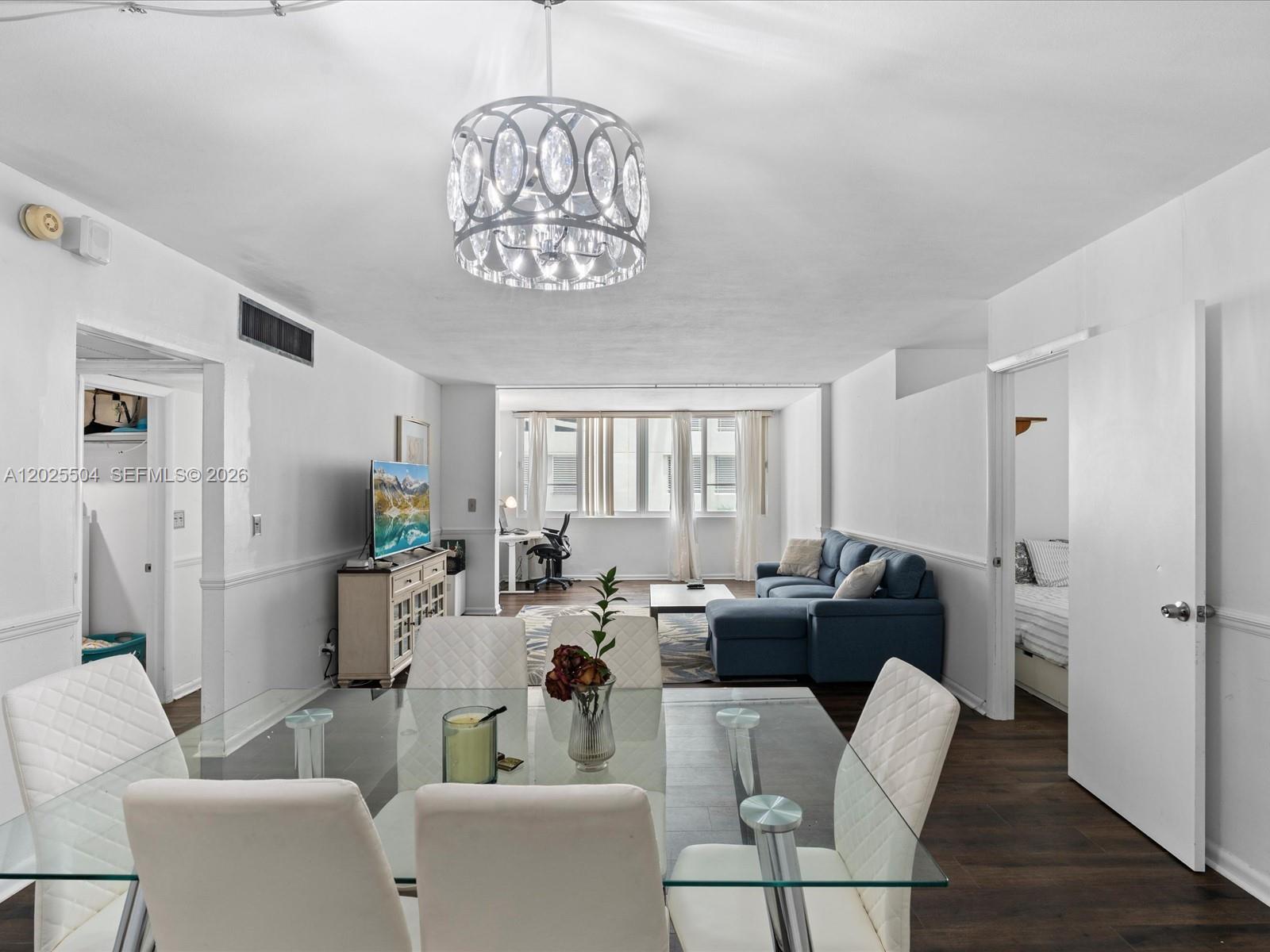 A dining area with a glass table leads into a living room with a blue sofa — 5005 Collins Ave # 222, Miami Beach FL 33140, MIAMI BEACH, FL