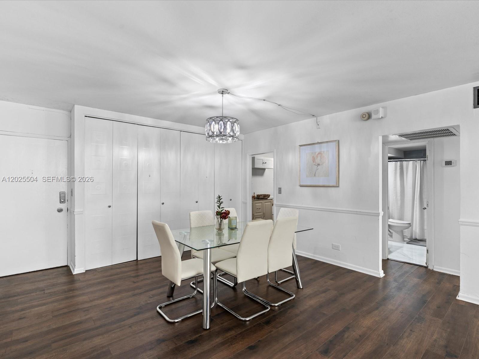 A dining area features a glass table, four white chairs, and dark wood flooring — 5005 Collins Ave # 222, Miami Beach FL 33140, MIAMI BEACH, FL