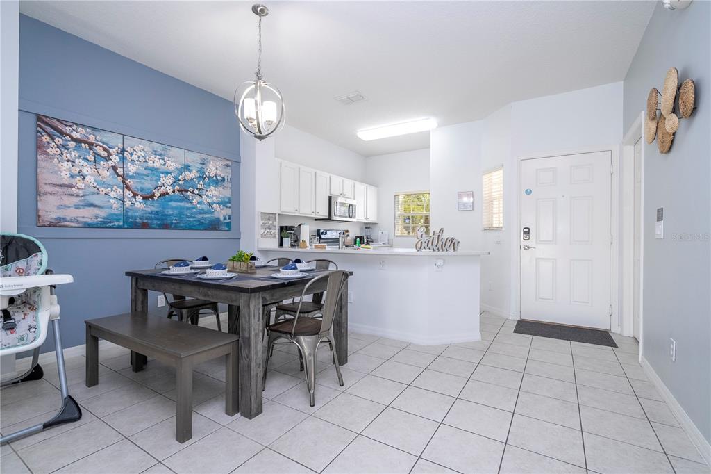 A white front door is positioned between a kitchen area and a hallway with light-colored tile — 1120 LAS FUENTES DRIVE, KISSIMMEE, FL
