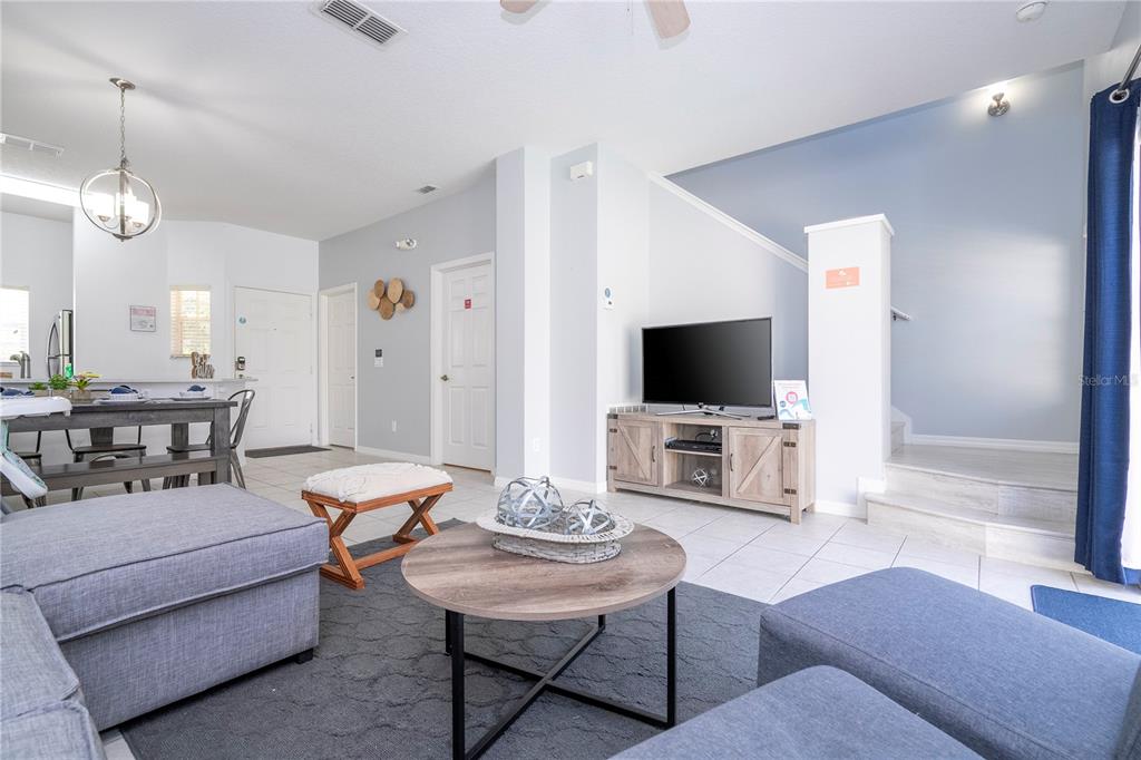 An open-concept kitchen, dining area, and living room with tile floors and a pool view — 1120 LAS FUENTES DRIVE, KISSIMMEE, FL