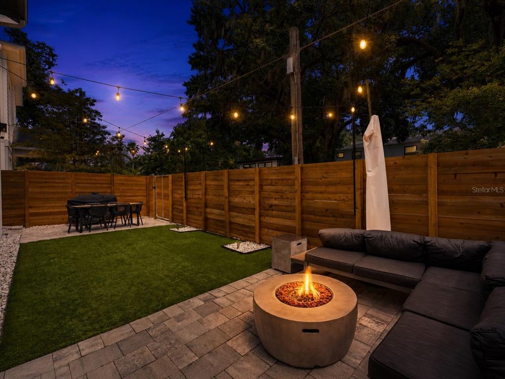 A backyard patio features a fire pit, sectional sofa, artificial turf, and string lights — 2401 AMHERST AVENUE, ORLANDO, FL