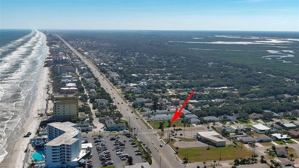 An aerial view shows a coastal town with a red arrow pointing to a vacant lot — 0 S ATLANTIC AVENUE, NEW SMYRNA BEACH, FL