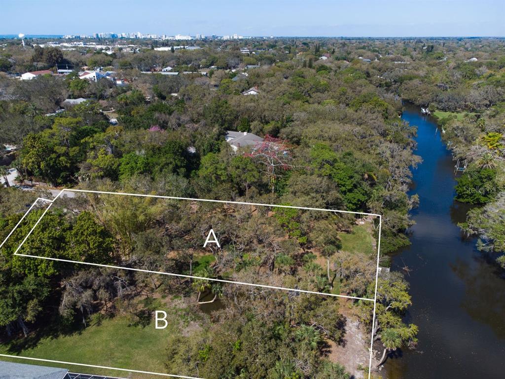 An aerial view shows two adjacent wooded lots bordering a river with a nearby neighborhood — 4407 S SHADE AVENUE, SARASOTA, FL