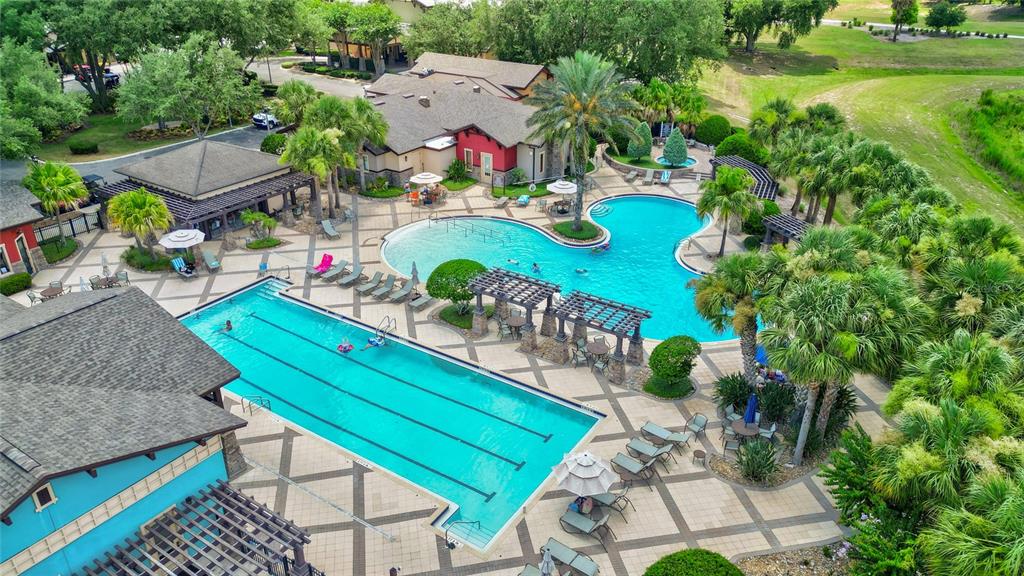 An aerial view shows a community pool area with two pools, lounge chairs, and pergolas — 4834 INDEPENDENCE TRAIL, LEESBURG, FL
