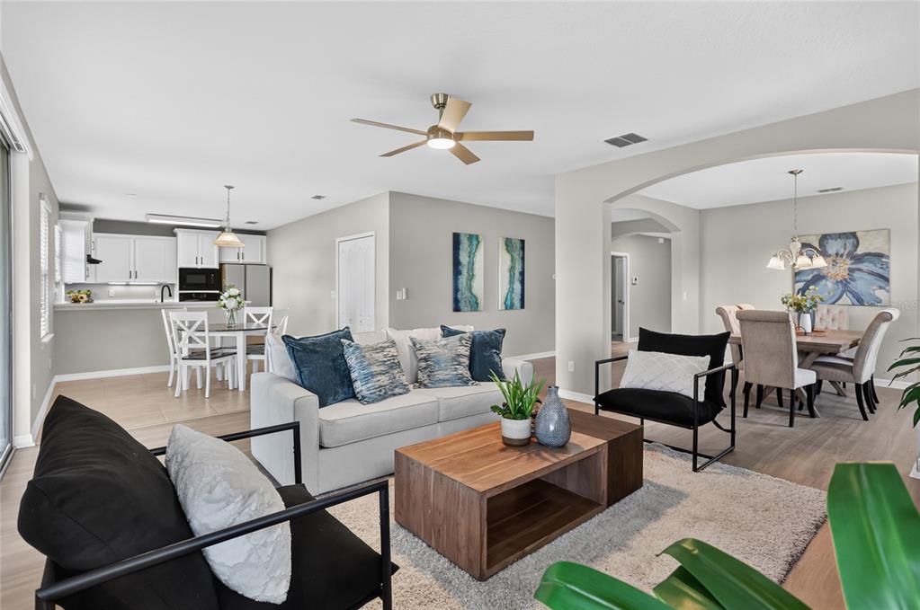 An open-concept living area features a sofa, coffee table, and dining space with neutral decor — 4834 INDEPENDENCE TRAIL, LEESBURG, FL