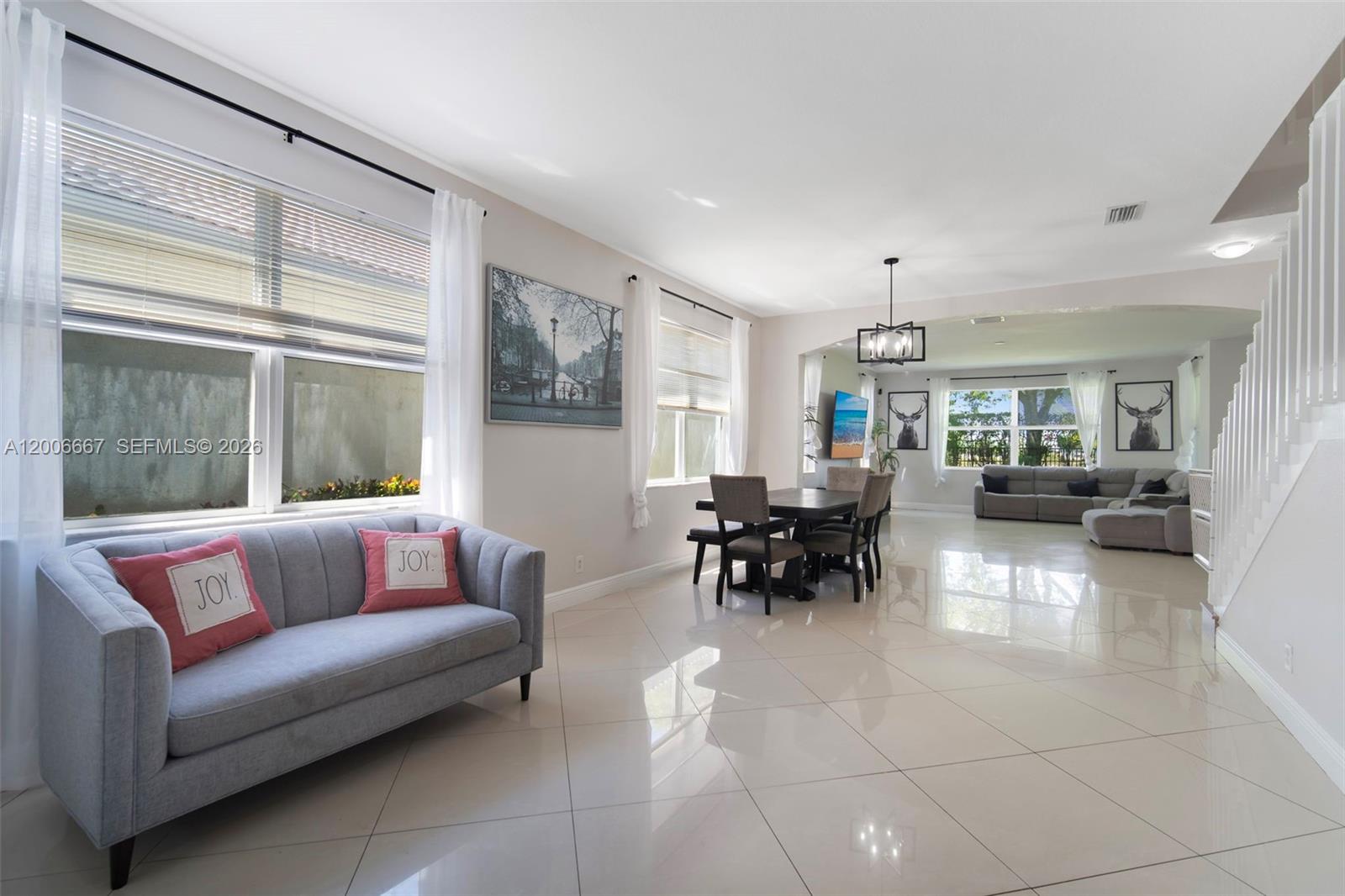 A bright, open-concept living and dining area features light tile flooring and neutral walls — 1225 Rosegate Blvd, Riviera Beach FL 33404, RIVIERA BEACH, FL