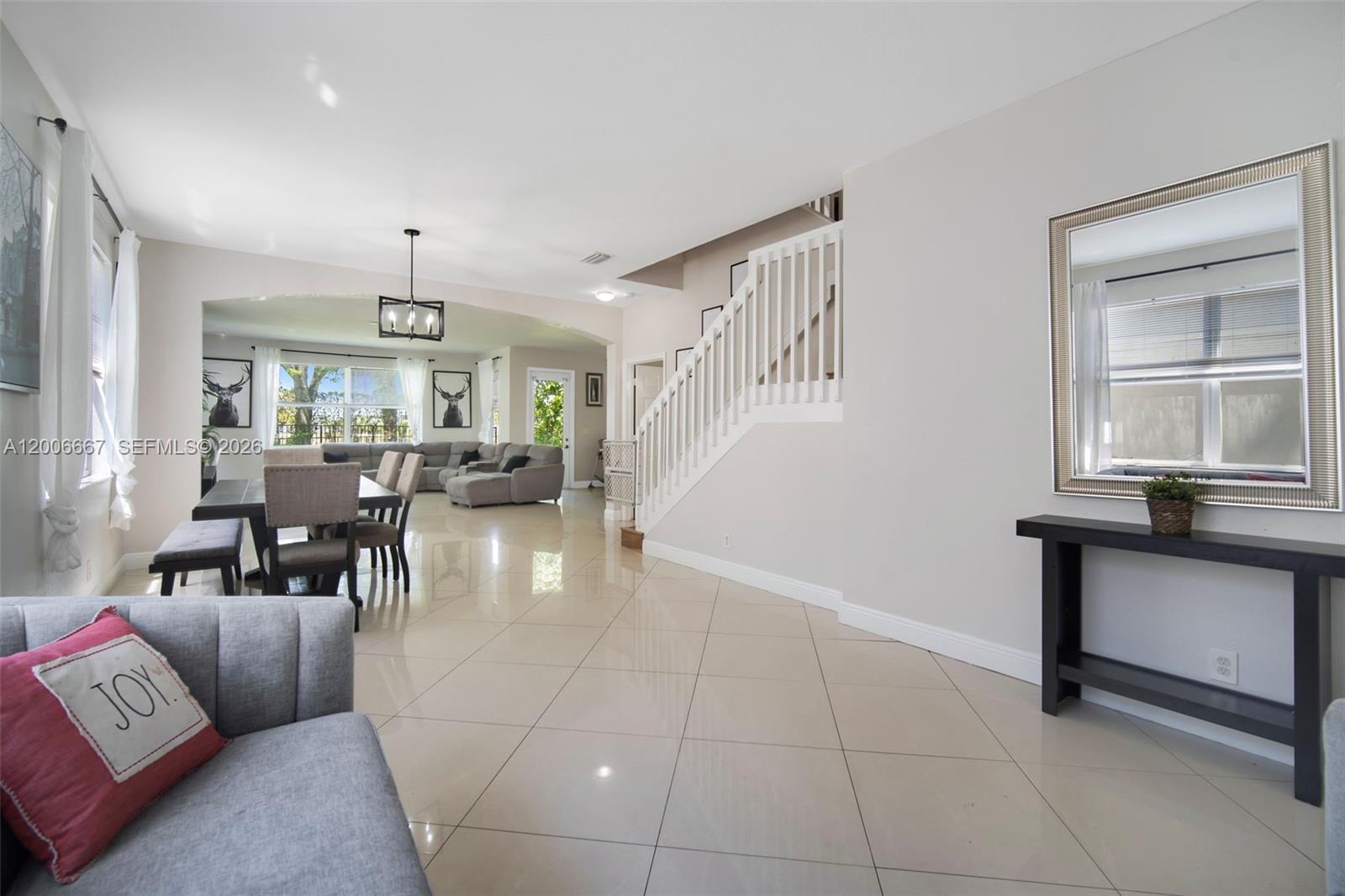 A bright living and dining area features tile floors, a staircase, and neutral walls — 1225 Rosegate Blvd, Riviera Beach FL 33404, RIVIERA BEACH, FL