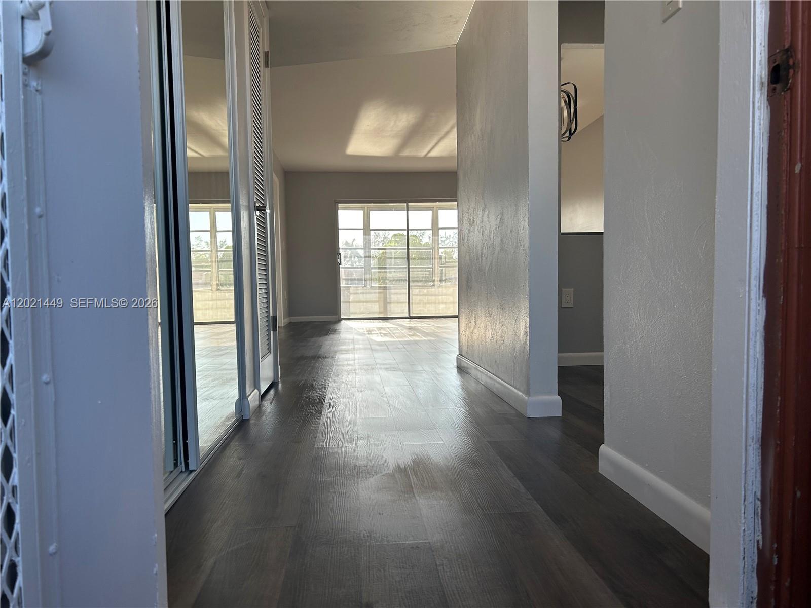 A hallway with dark wood-look flooring leads toward a room with a sliding glass door — 2831 E Sunrise Lakes Dr # 309, Sunrise FL 33322, SUNRISE, FL