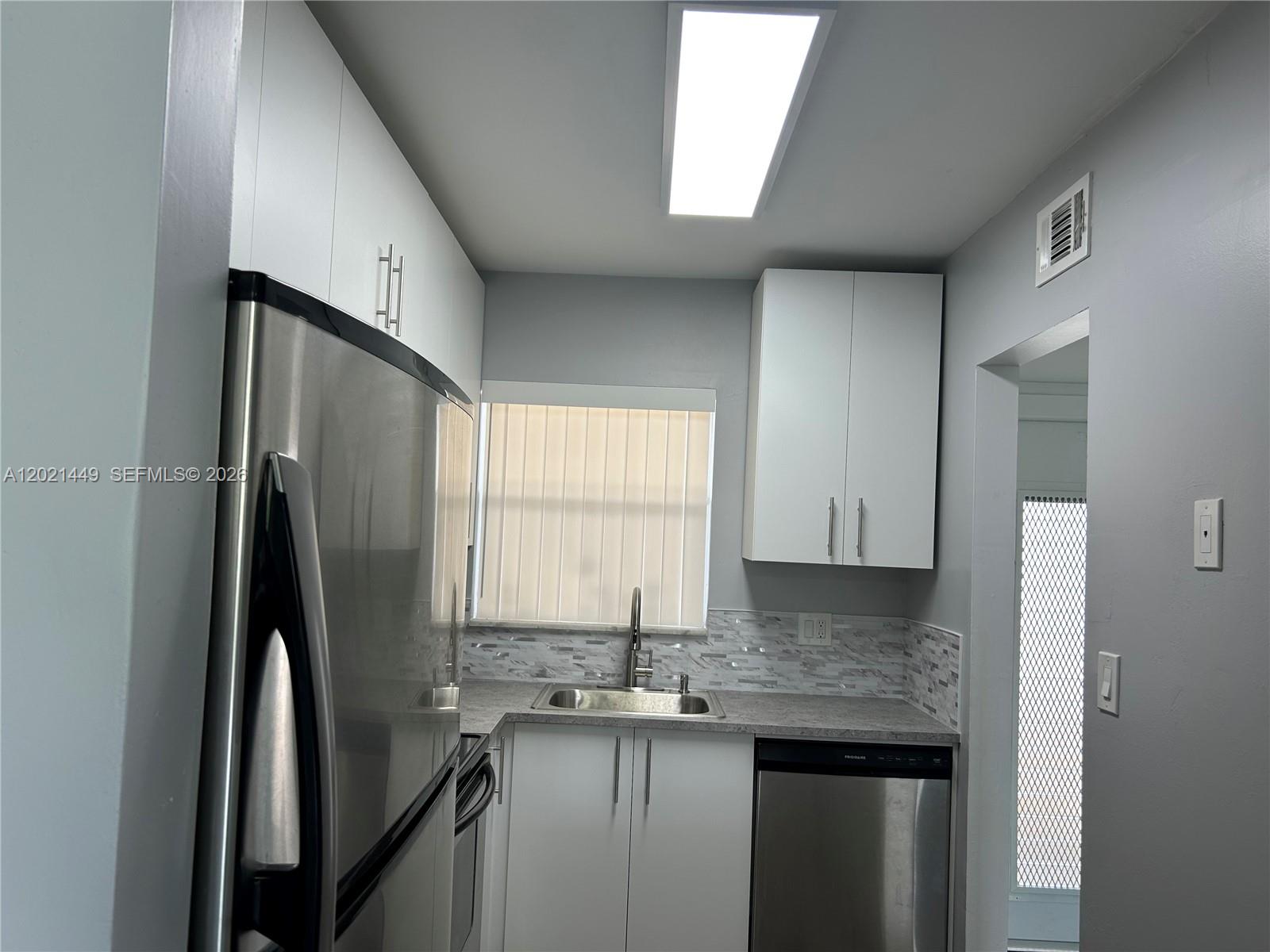 A kitchen features white cabinets, stainless steel appliances, a gray countertop, and a tiled backsplash — 2831 E Sunrise Lakes Dr # 309, Sunrise FL 33322, SUNRISE, FL