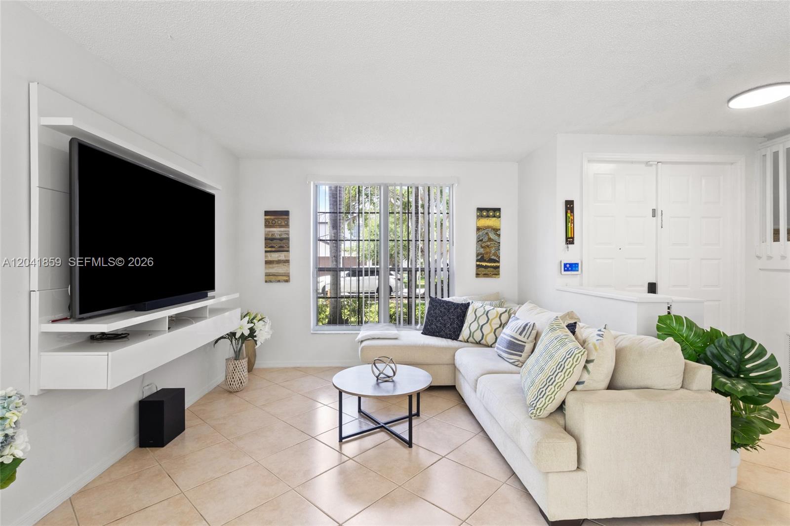 A living room features a wall-mounted television, a sectional sofa, and tile flooring — 18222 SW 27th Street, Miramar FL 33029, MIRAMAR, FL