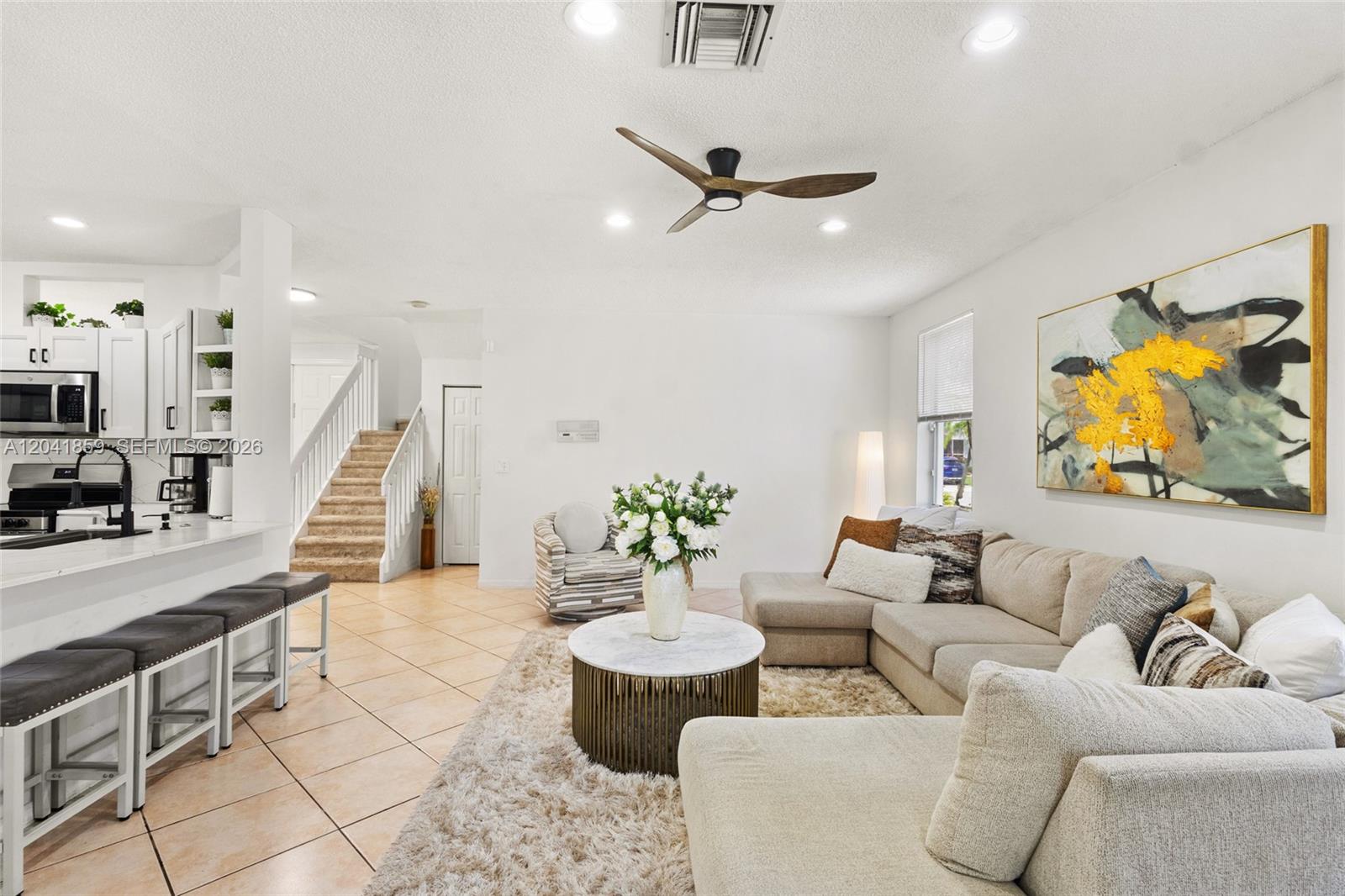 A bright living room features a sectional sofa, a marble coffee table, and a staircase — 18222 SW 27th Street, Miramar FL 33029, MIRAMAR, FL