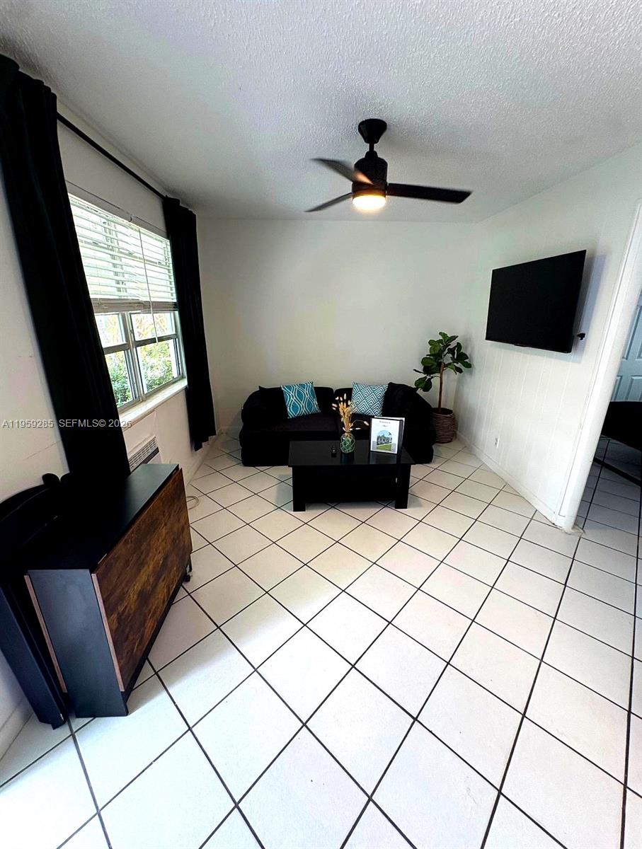 A living room features a black sofa, a coffee table, and white tiled flooring — 3210 Canal Dr # 7, Pompano Beach FL 33062, POMPANO BEACH, FL