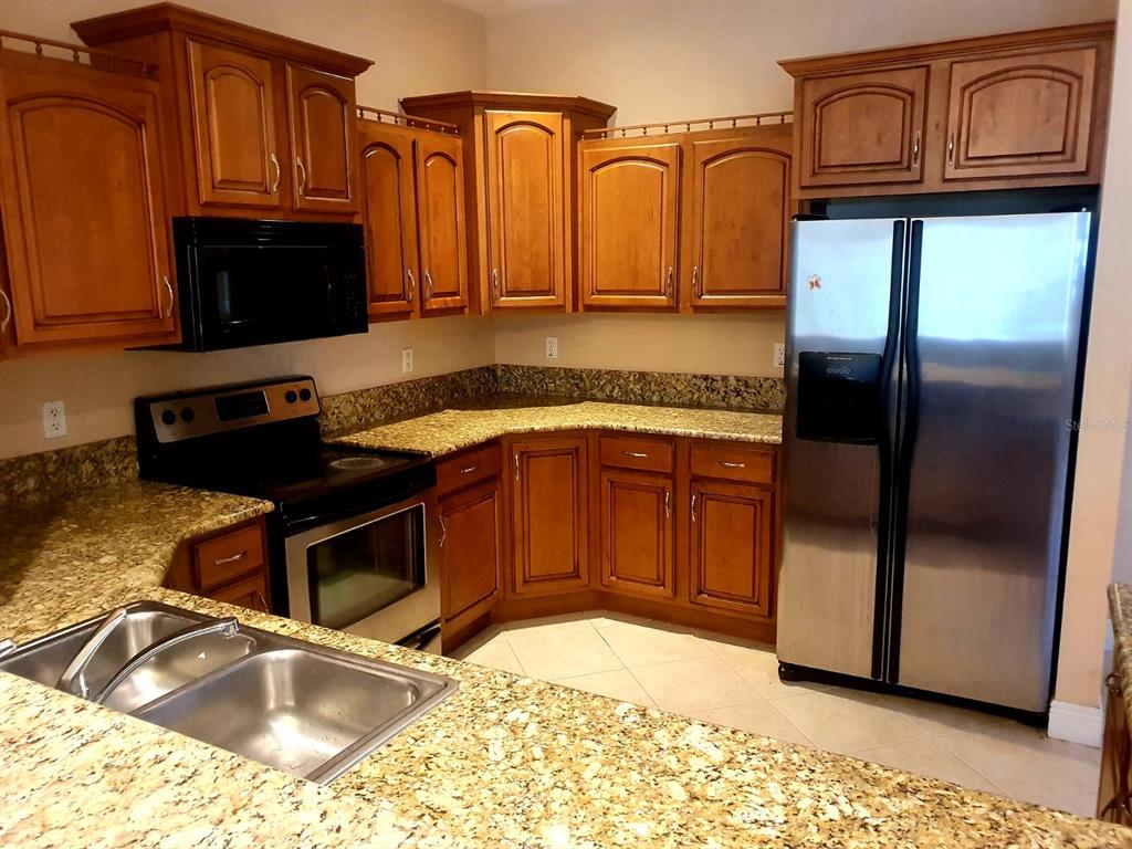 A kitchen features wood cabinets, granite countertops, and stainless steel appliances — 4706 MACKEREL DRIVE, SEBRING, FL