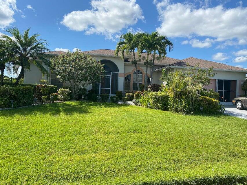 A single-story house with a lawn, palm trees, and a driveway under a blue sky — 5640 NW Commodore Terrace, Port St. Lucie FL 34983, PORT ST. LUCIE, FL