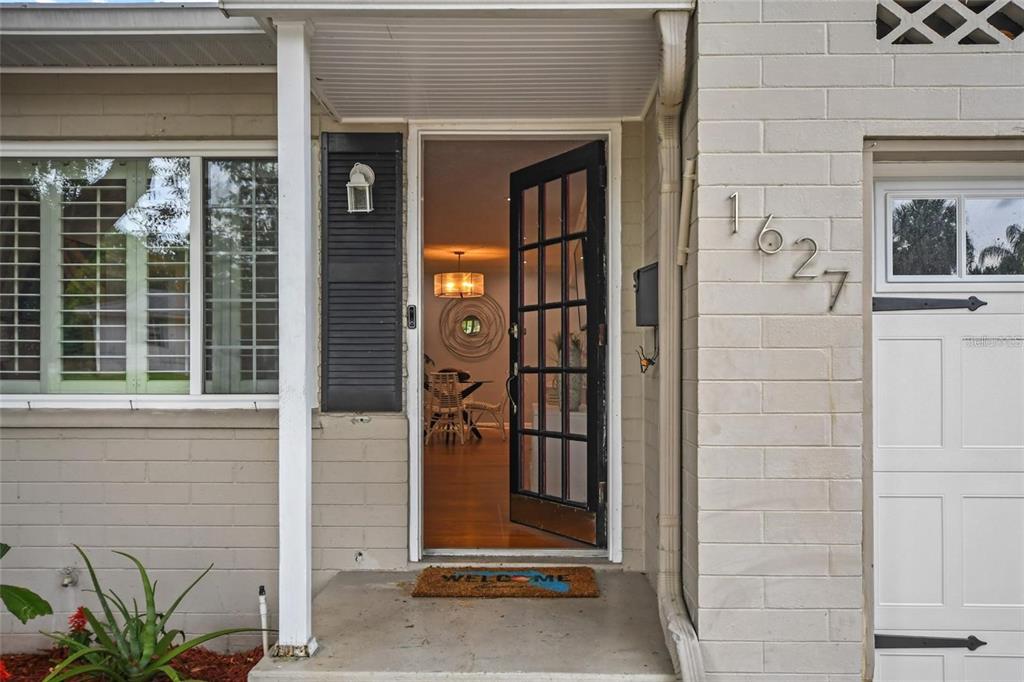 A view of a house exterior featuring a brick facade, a black-framed door, and house numbers — 1627 ORANGE AVENUE, WINTER PARK, FL