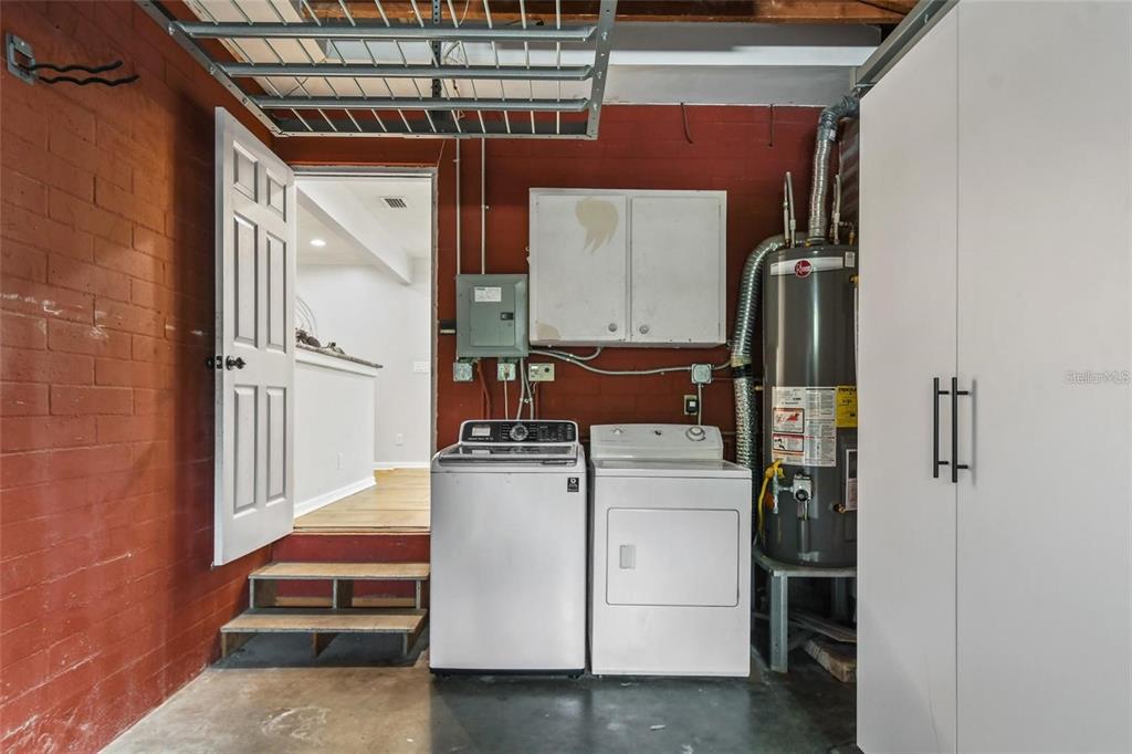 A laundry area features a washer, dryer, and water heater against a red brick wall — 1627 ORANGE AVENUE, WINTER PARK, FL