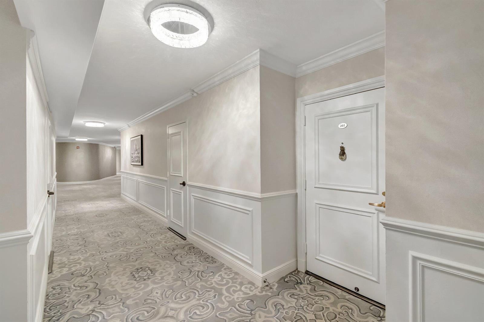 A carpeted hotel hallway features white paneled walls, recessed ceiling lights, and a numbered door — 4740 S Ocean Boulevard # 202, Highland Beach FL 33487, HIGHLAND BEACH, FL