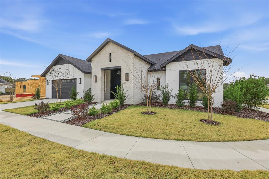 A modern one-story house with white brick, dark trim, and a front-facing garage — 1001 SW 120TH DRIVE, GAINESVILLE, FL