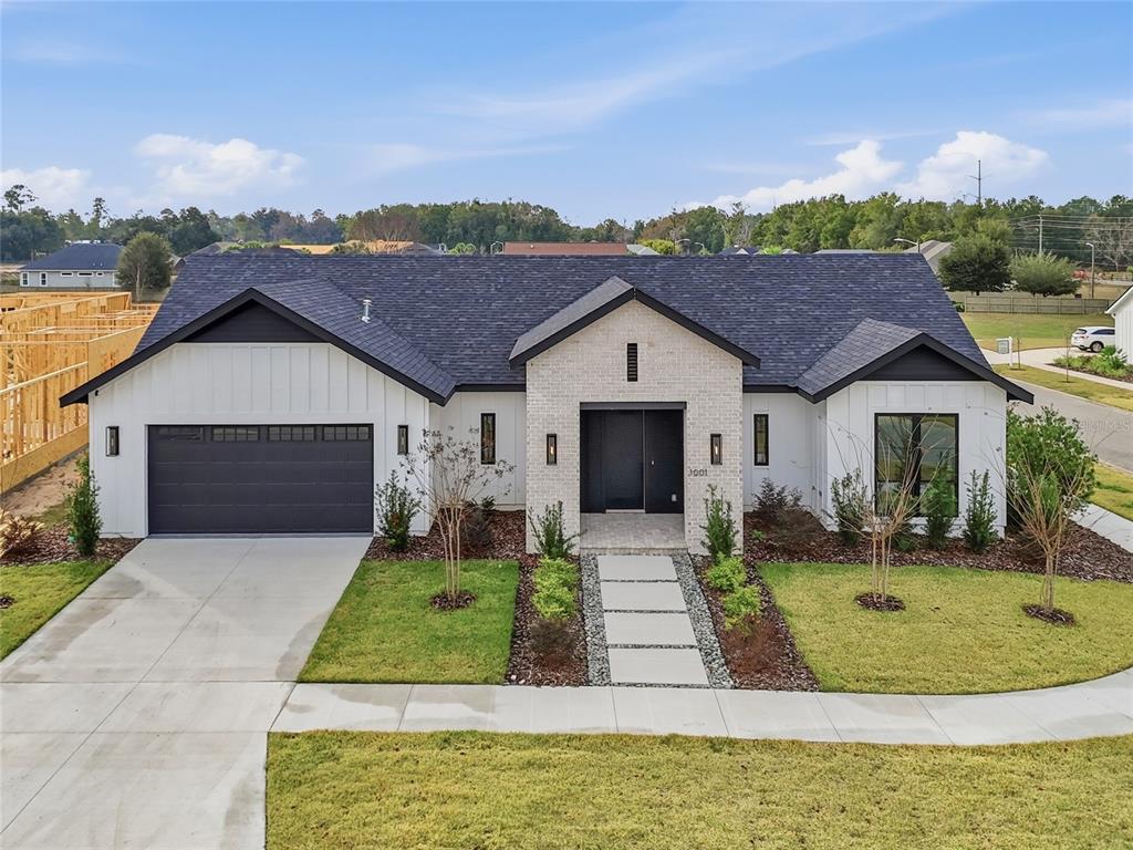 A modern single-story house with a white brick facade, dark roof, and a two-car garage — 1001 SW 120TH DRIVE, GAINESVILLE, FL