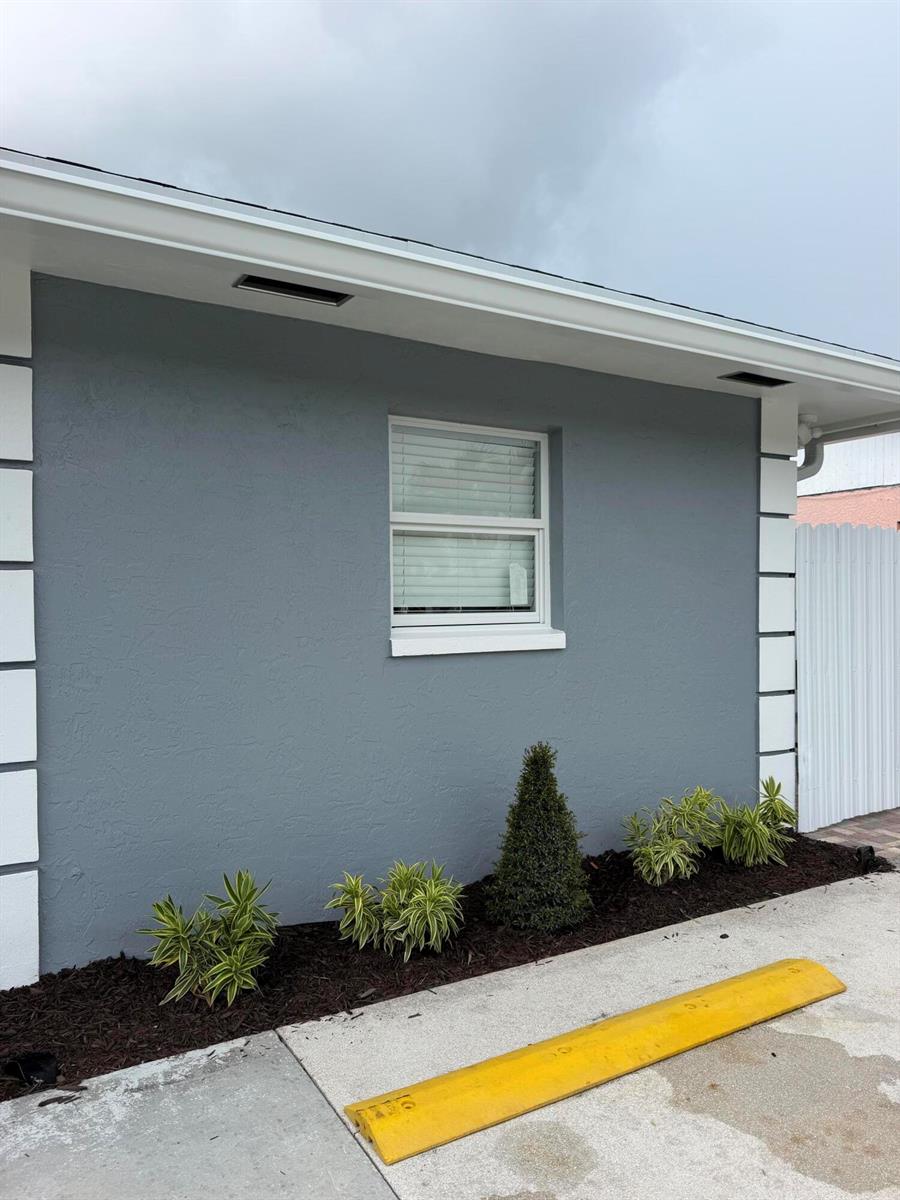 A gray exterior wall with white corner accents, a single window, and small landscaping plants — 5612 S 36th Street, FL 33463, FL