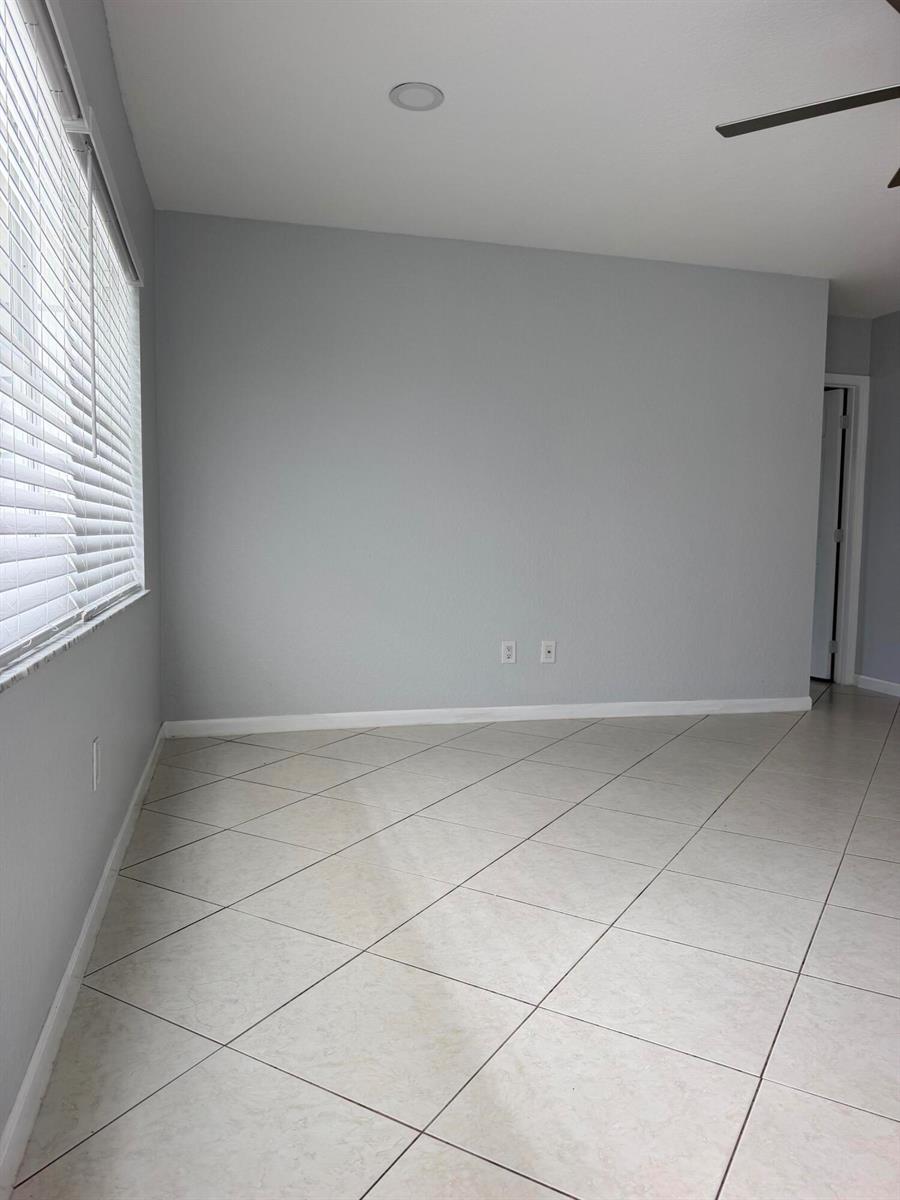An empty room with light gray walls, tile flooring, and a window with blinds — 5612 S 36th Street, FL 33463, FL