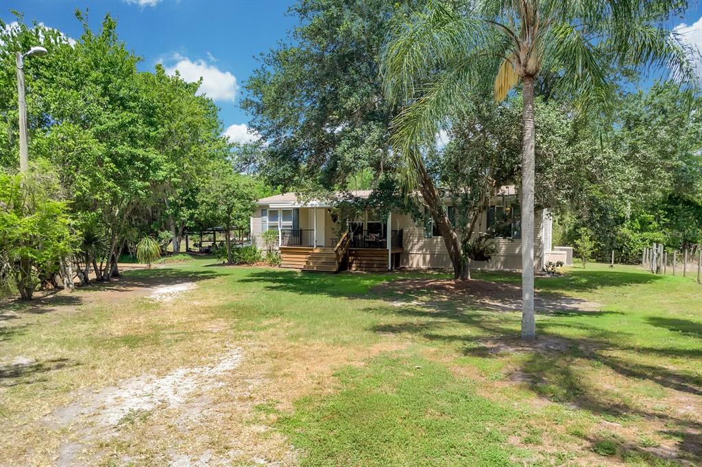 A single-story house with a wooden deck sits on a grassy lot with trees — 4350 FANNY BASS ROAD, ST CLOUD, FL