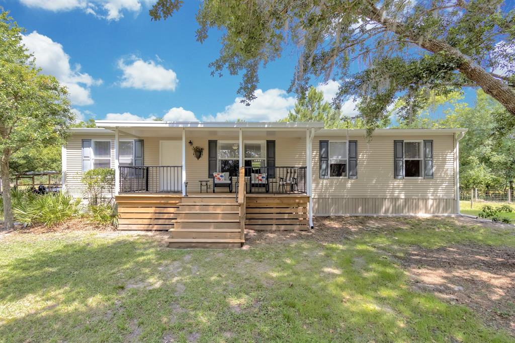 A single-story manufactured home with a wooden front deck and stairs under a metal roof — 4350 FANNY BASS ROAD, ST CLOUD, FL