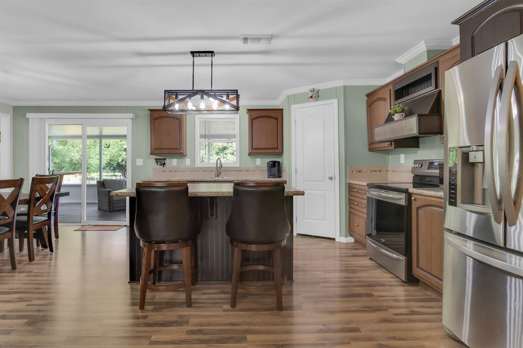 A kitchen features wood cabinets, stainless steel appliances, a center island, and wood-look flooring — 4350 FANNY BASS ROAD, ST CLOUD, FL