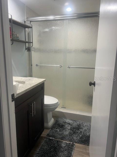 A bathroom features a dark wood vanity, a toilet, and a glass-enclosed walk-in shower — 4016 LAKE BOULEVARD, CLEARWATER, FL